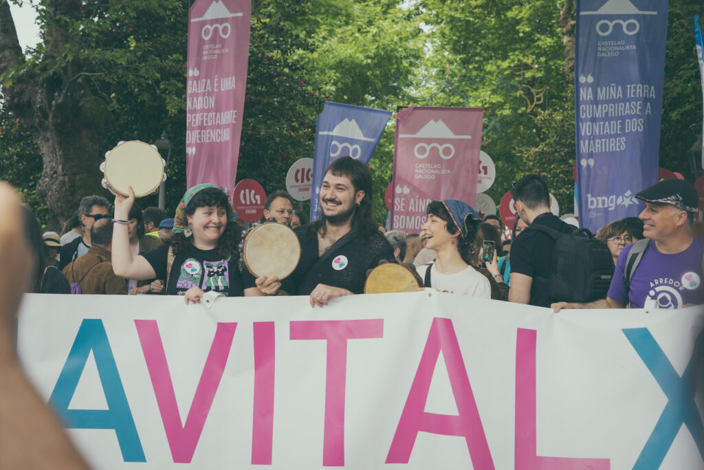 Varias persoas sosteñen a faixa principal da manifestación con pandeiretas.