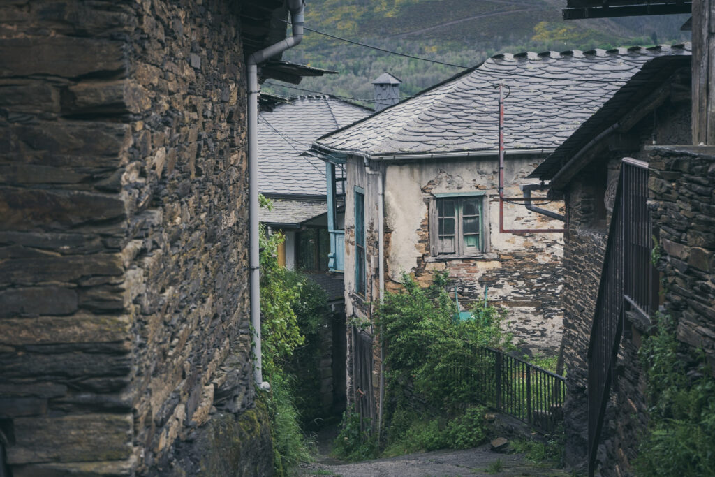 Pista en Vilamor. Pódese observar a pendiente do terreo e casas de pedra antigas.