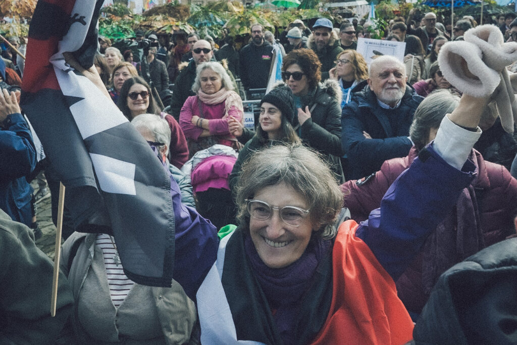 En primeiro plano unha señora que sostén unha bandeira e ten os brazos en alto.