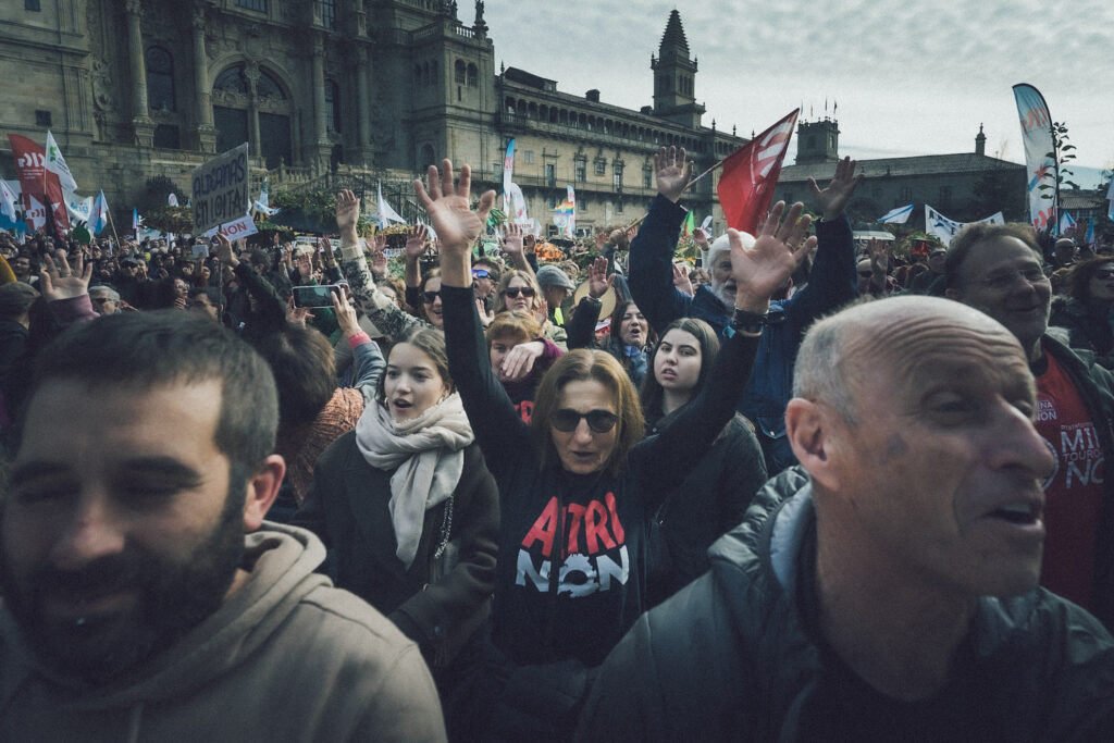 Multitude na Praza do Obradoiro. No centro da imaxe, unha muller cunha camiseta de Altri Non coas mans erguidas.